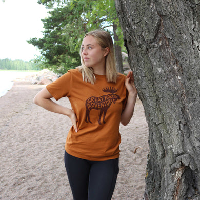 Tyttö luonnossa jolla päällä paahdettu oranssi t-paita jossa iso hirvipainatus