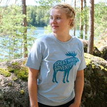Lataa kuva Galleria-katseluun, Tyttö luonnossa jolla päällä vaaleansininen t-paita jossa iso hirvipainatus
