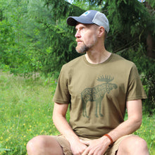 Lataa kuva Galleria-katseluun, Mies luonnossa jolla päällä metsänvihreä t-paita jossa iso hirvipainatus

